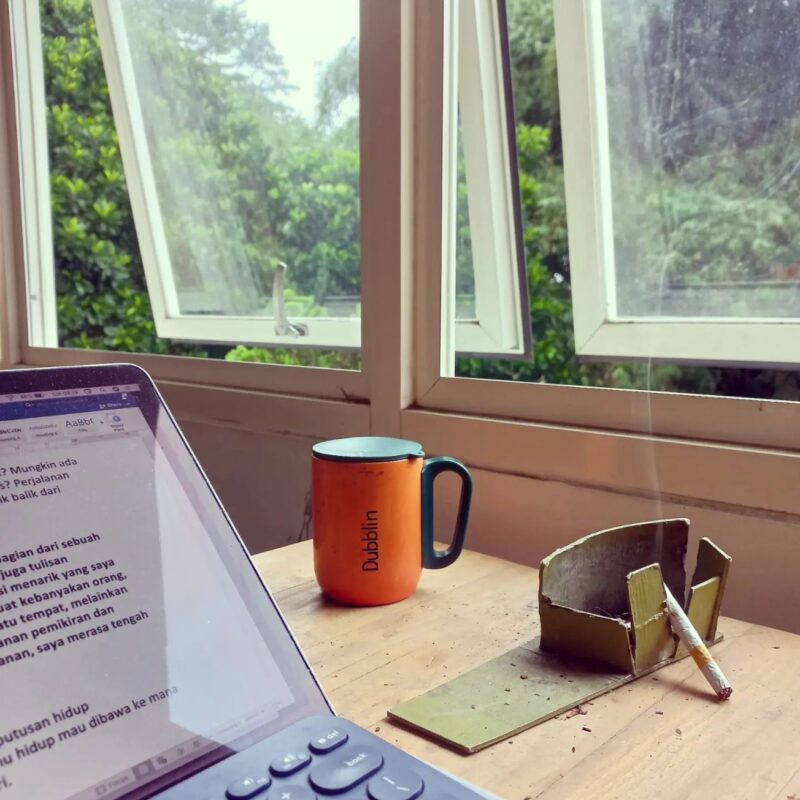 A laptop, a mug, and cigarettes